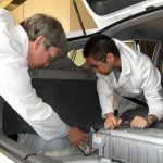 Engineers refitting a plug-in hybrid car with a larger battery pack and charger